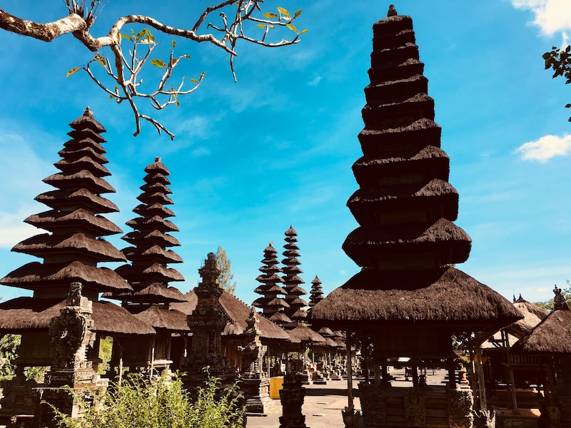 Traditional Balinese Hindu temple Pura Taman Ayun with its iconic multi-tiered meru towers under a clear blue sky.