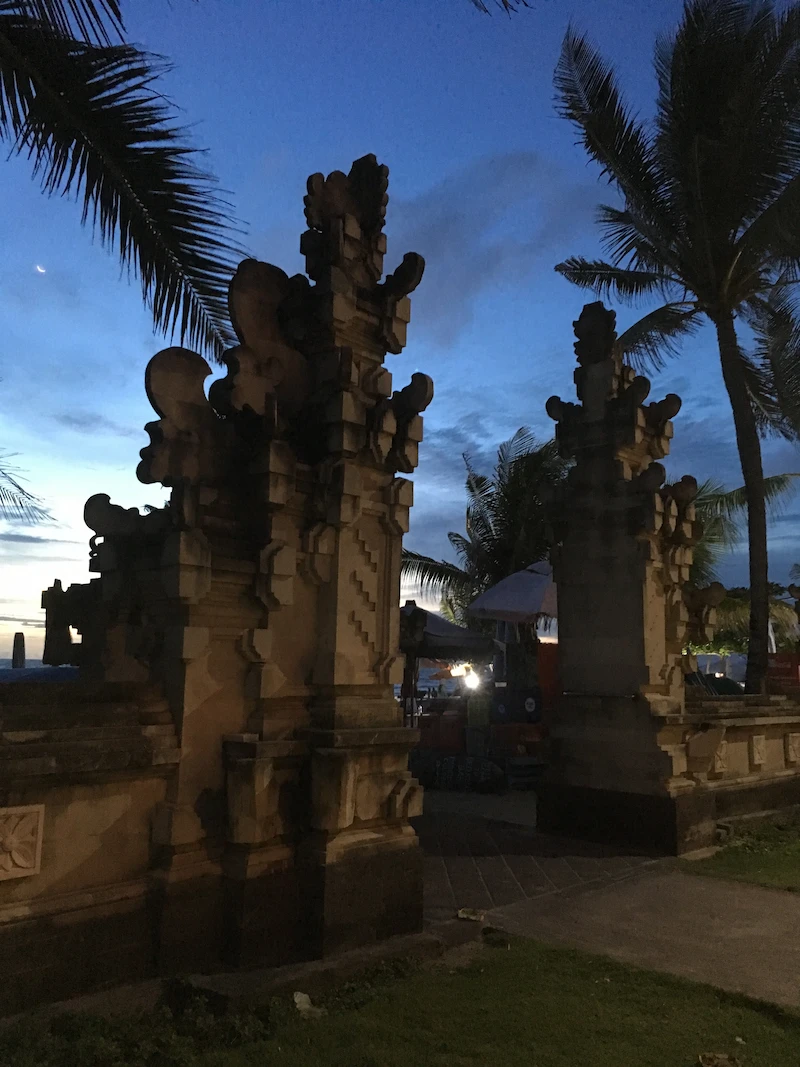 An iconic Balinese stone gate (candi bentar) at sunset on a beach, symbolizing the paradise setting that can be a major distraction for remote workers in Bali.