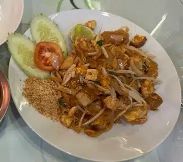 A classic Thai meal set featuring a large plate of Pad Thai noodles