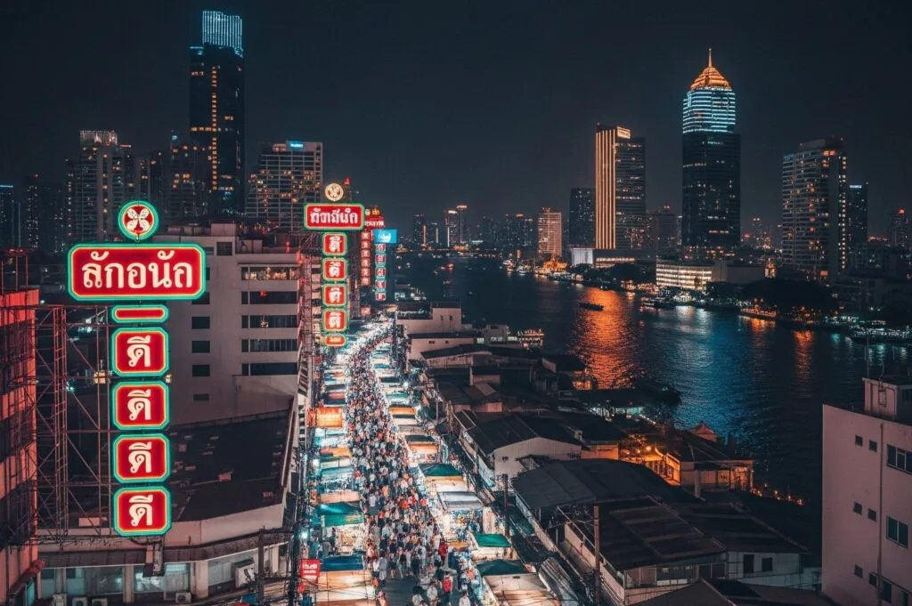 Bangkok night market beside a river and buildings at the back