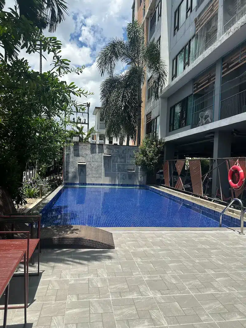 Modern outdoor swimming pool at a condo complex in Chiang Mai, a common amenity included in monthly rental prices in areas like Changklan or Nimman.