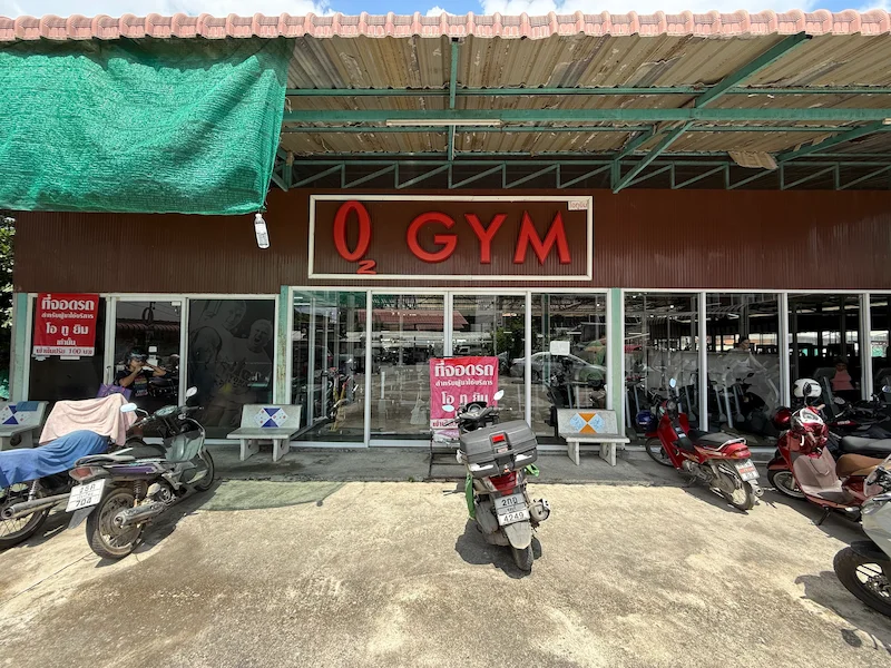 Picture of the O2 Gym building in Chiang Mai, Thailand. Picture shows the entrance area and parking area of the gym.