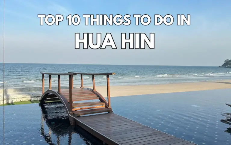 A serene infinity pool with a small wooden bridge leading toward a wide, sandy beach and the calm blue ocean in Hua Hin, Thailand.