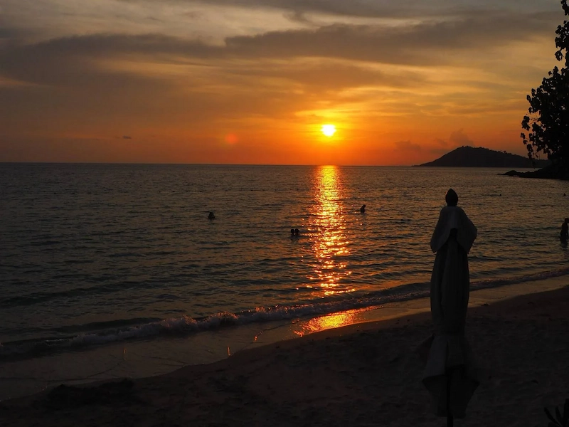 A peaceful orange sunset over the calm water of Ao Hin Kok beach on Koh Samet.