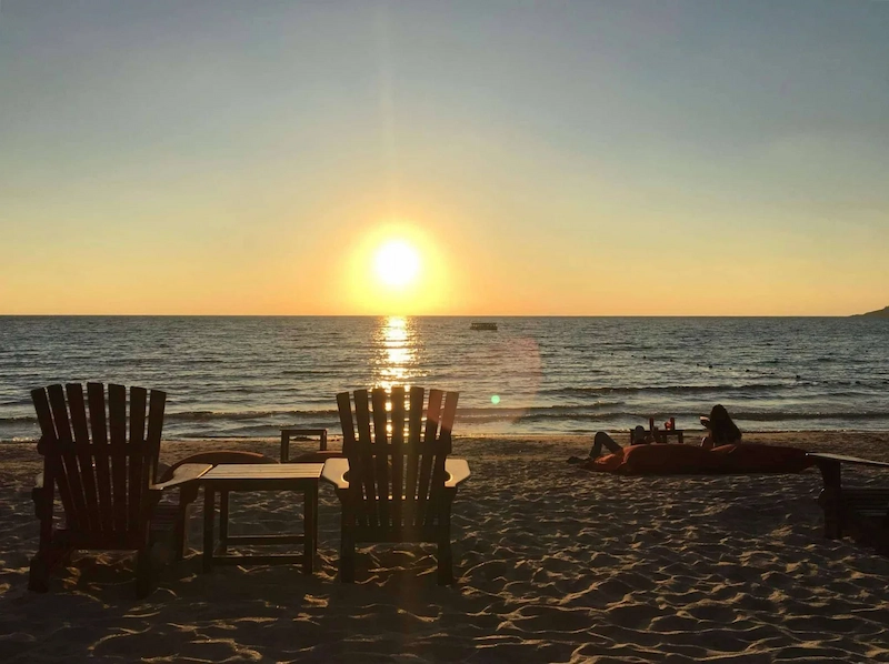 A solo traveler watching the final moments of a beautiful sunset at Ao Phrao beach, Koh Samet.