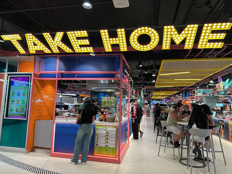 Photo of the food court at the basement level of the mall, with the words "take home" in bold