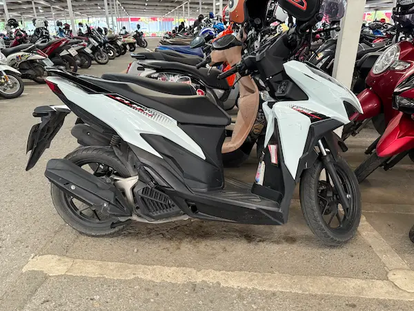 Picture of a white Honda Click 125 in a parking lot in Thailand.
