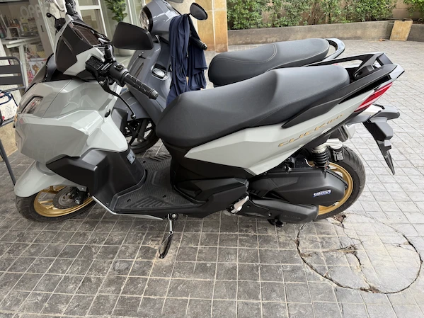 Picture of a white/golden Honda Click 160 in a parking lot in Thailand.