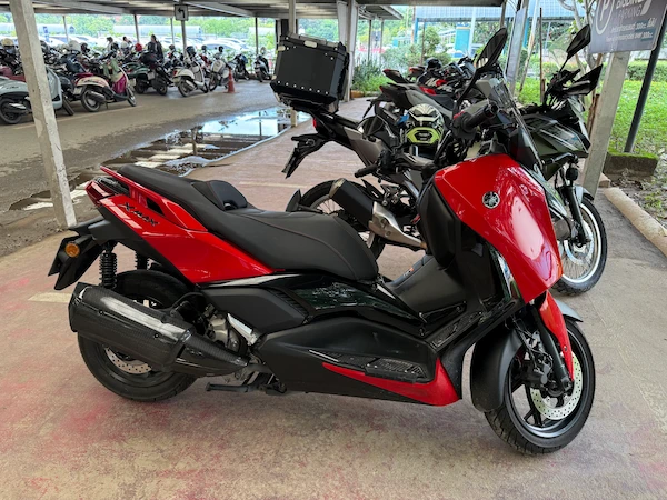 Picture of a red Yamaha XMAX in a parking lot in Thailand.