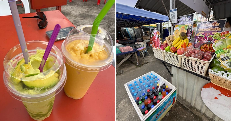 Freshly made avocado and mango smoothies in plastic cups from a Krabi night market stall. The stall in the background has fresh fruit and a cooler of drinks.