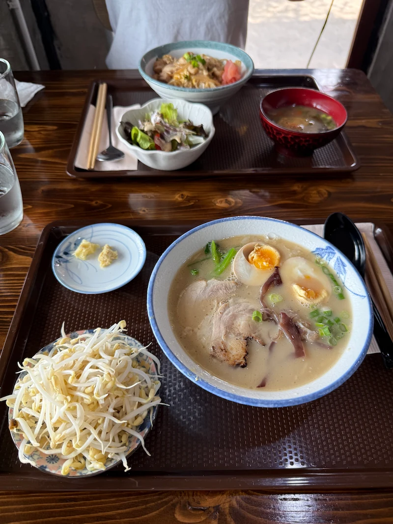 A lunch set at Kinsou Ramen featuring a bowl of tonkotsu ramen with bean sprouts, soft-boiled egg, and chashu pork, served on a wooden tray.