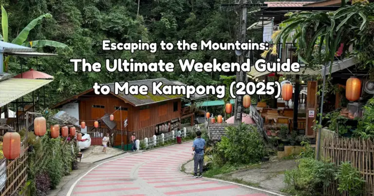 A view looking down the main winding road of Mae Kampong village, lined with traditional wooden houses, red lanterns, and lush greenery.