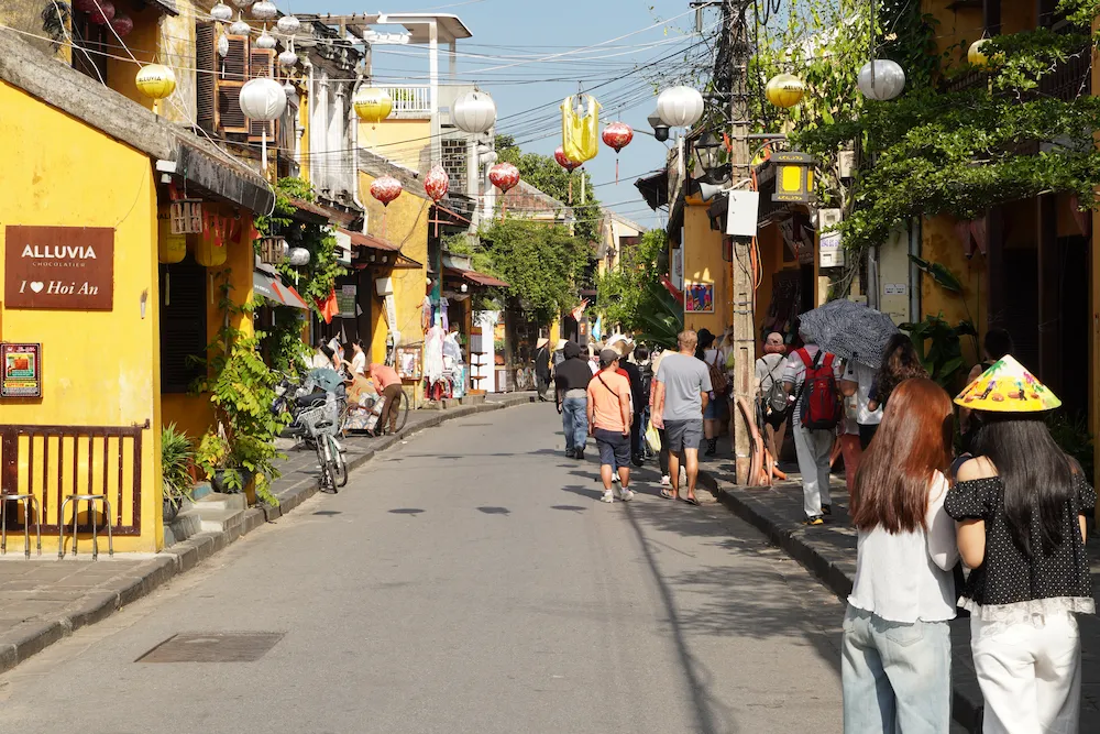 Tourists walking along a lantern-decorated street past the Alluvia chocolatier in Hoi An Ancient Town