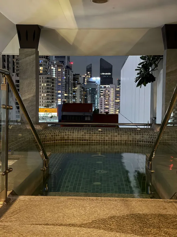 Small covered kids pool at Jasmine City Hotel with a view of the Bangkok skyline at night