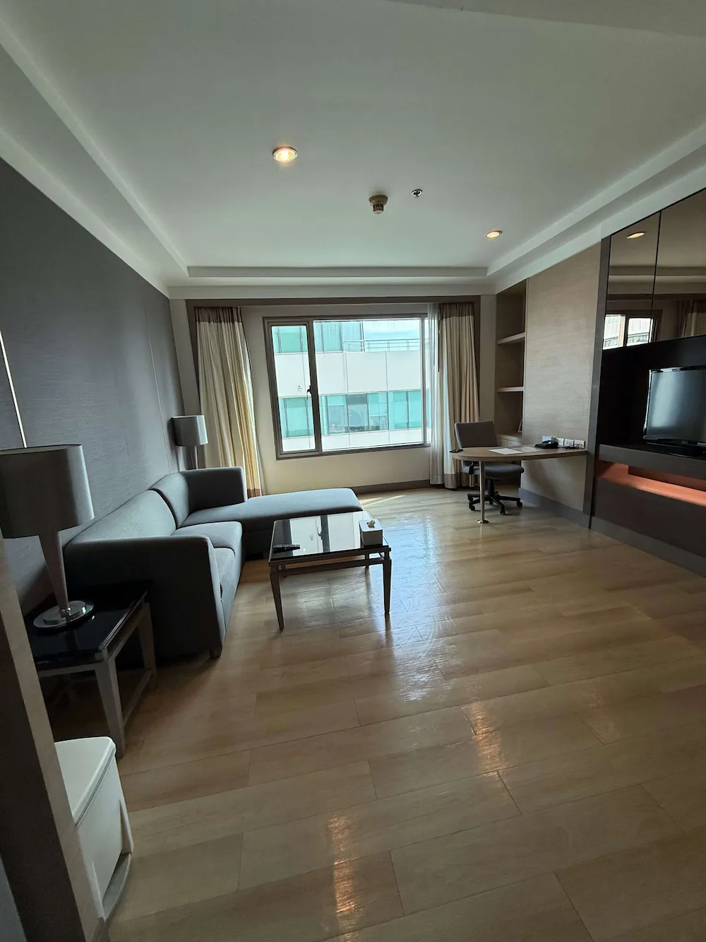 Living room with sofa, work desk and TV in a suite at Jasmine City Hotel, Bangkok