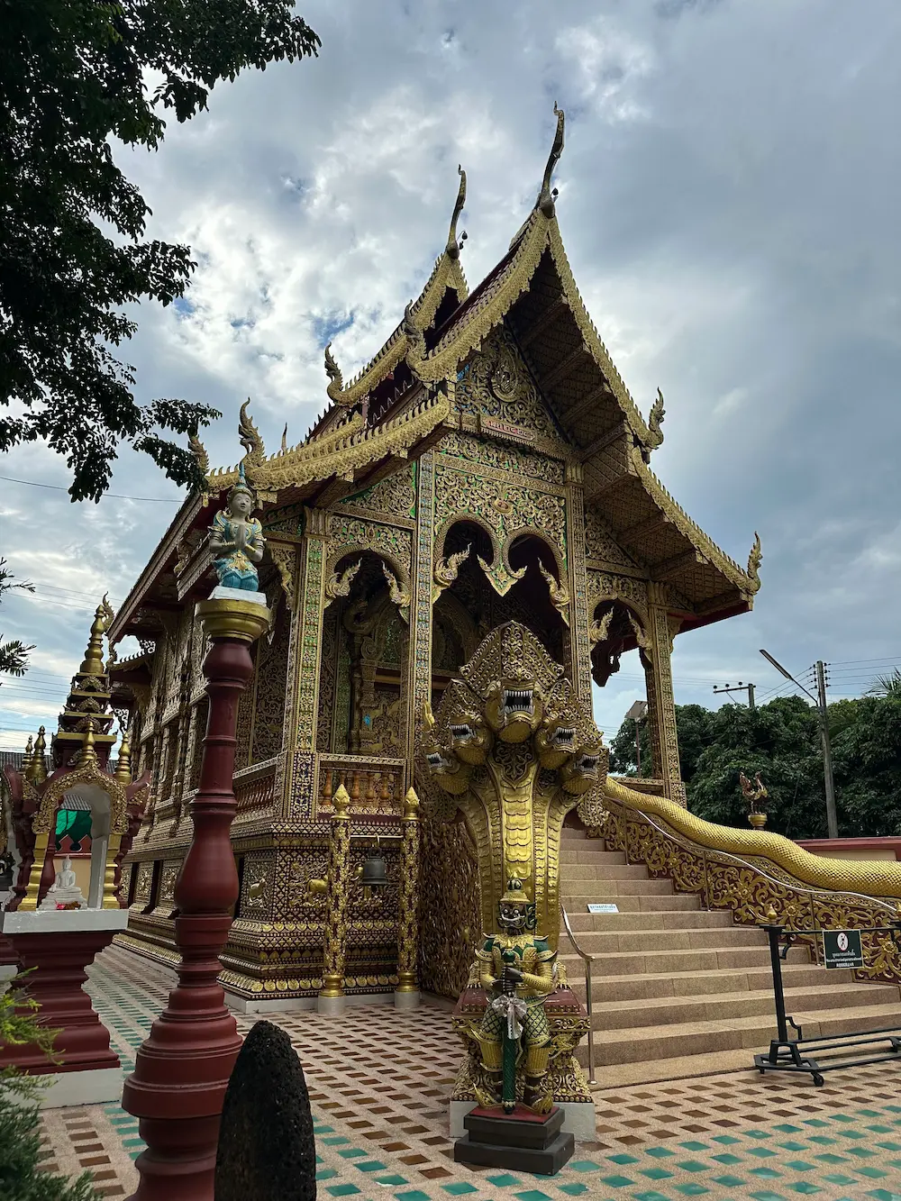 Golden Kuti Song Lanna building at Wat Sri Don Moon, with a seven-headed naga staircase and a guardian giant statue