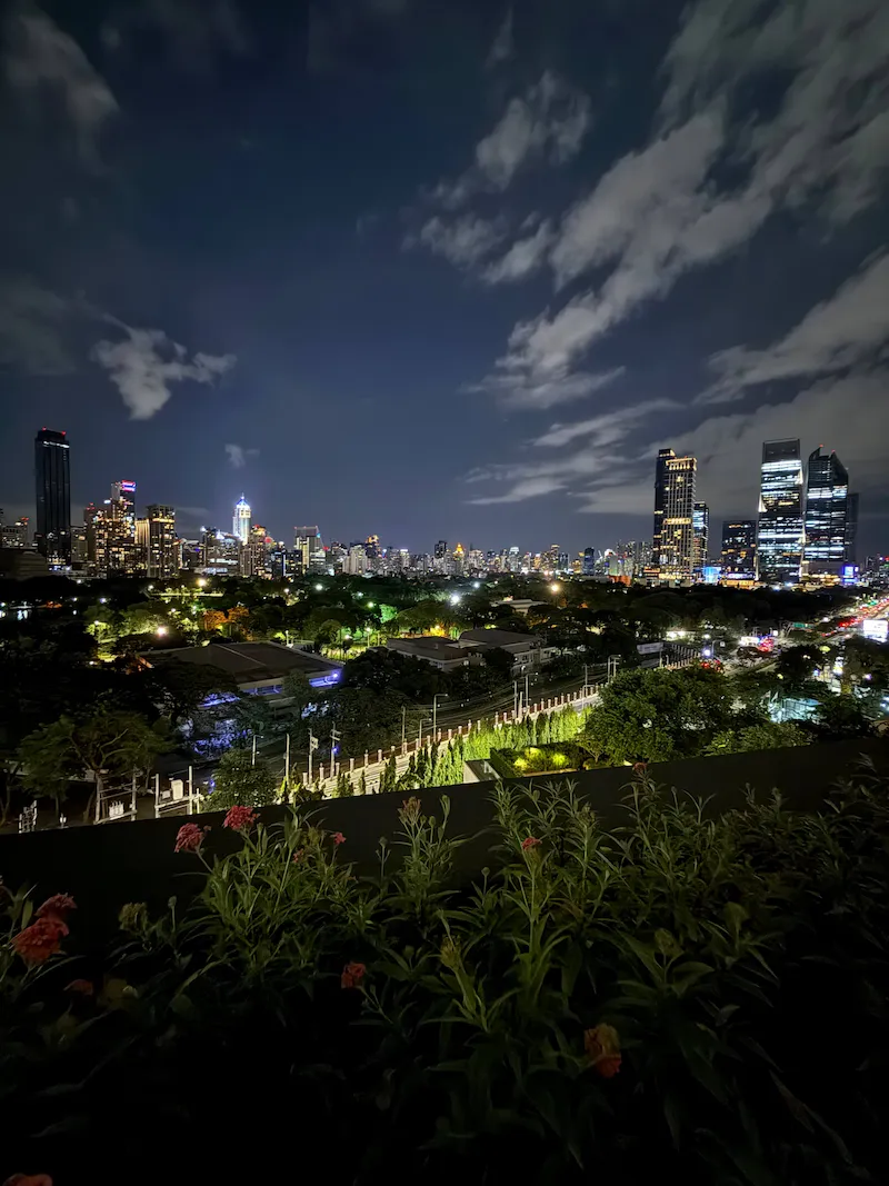 Evening traffic on Rama IV Road beside Lumpini Park under a full moon, seen from the Dusit Central Park rooftop
